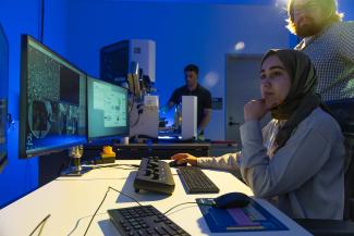 Student researchers looking at computer screen with technology it the background.