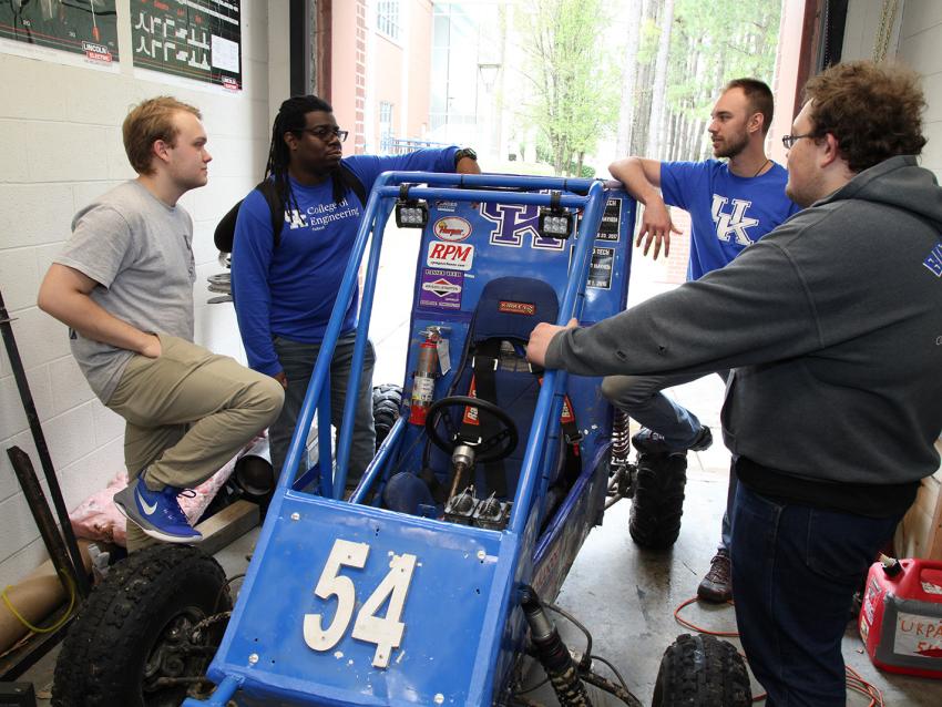 Several students standing around a race car
